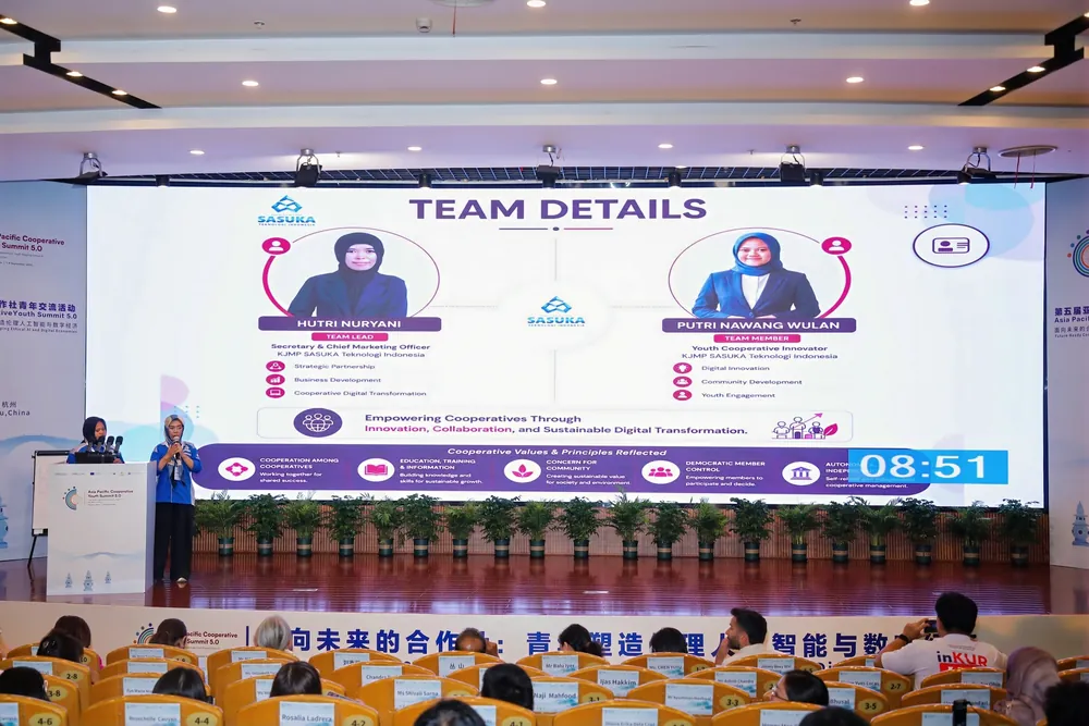 Layar besar menampilkan profil tim KJMP Sasuka Teknologi Indonesia saat pitching di Auditorium ZJIET, dengan penonton berkaos inKUR di barisan depan