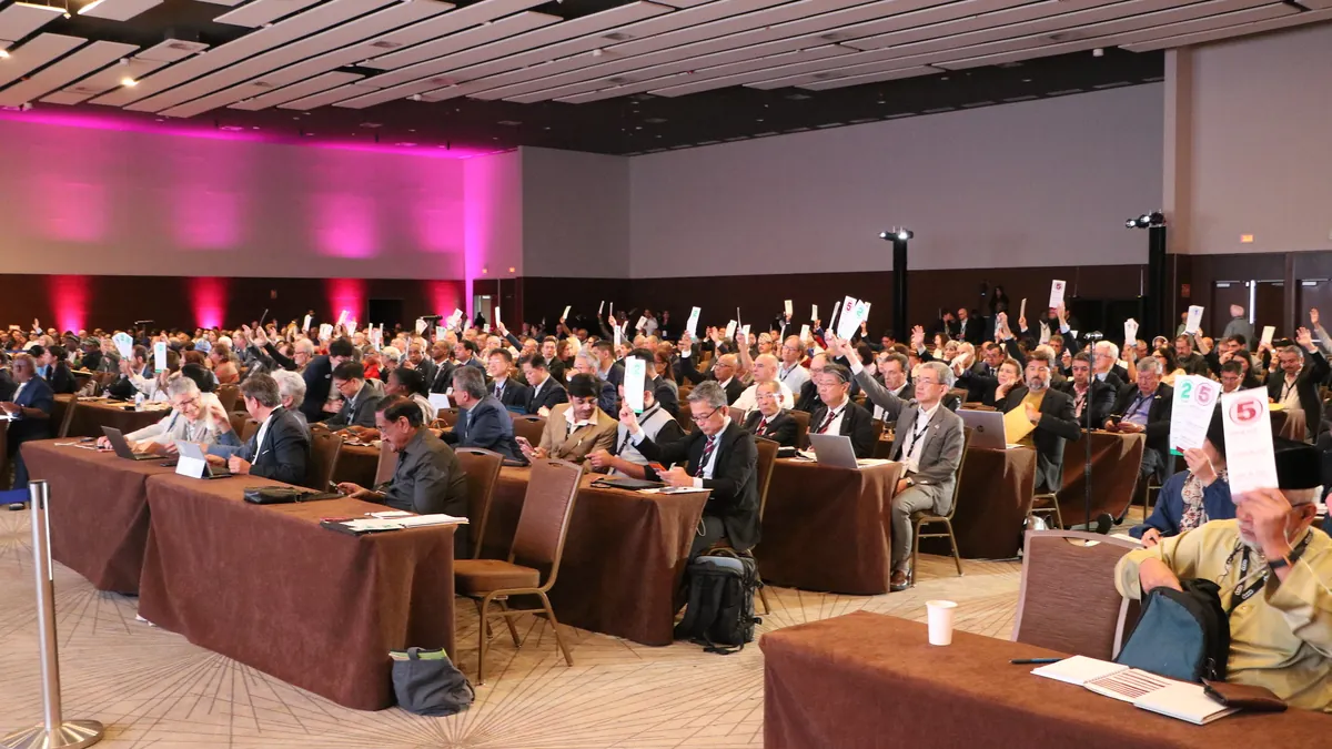 Para pemegang suara mengangkat kartu suara di sidang ICA General Assembly, Panama City, 15 September 2026 (foto: International Cooperative Alliance) / Voters raise their voting cards at the ICA General Assembly, Panama City, 15 September 2026 (photo: International Cooperative Alliance)